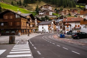 Picturesque street in a Dolomites village surrounded by lush hills, showcasing charming alpine houses.