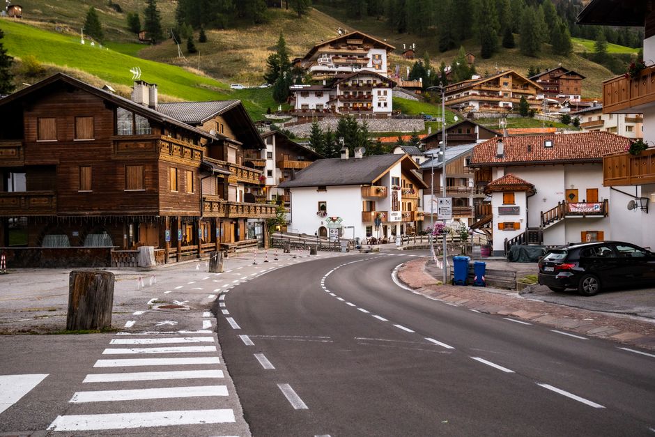 Picturesque street in a Dolomites village surrounded by lush hills, showcasing charming alpine houses.