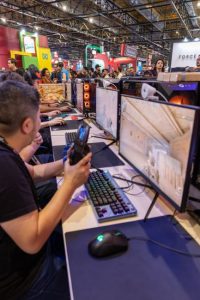 A vibrant gaming convention featuring players engaged with computers and gaming accessories.