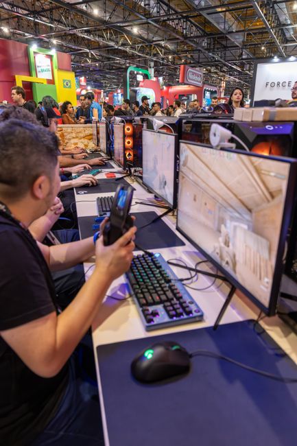 A vibrant gaming convention featuring players engaged with computers and gaming accessories.